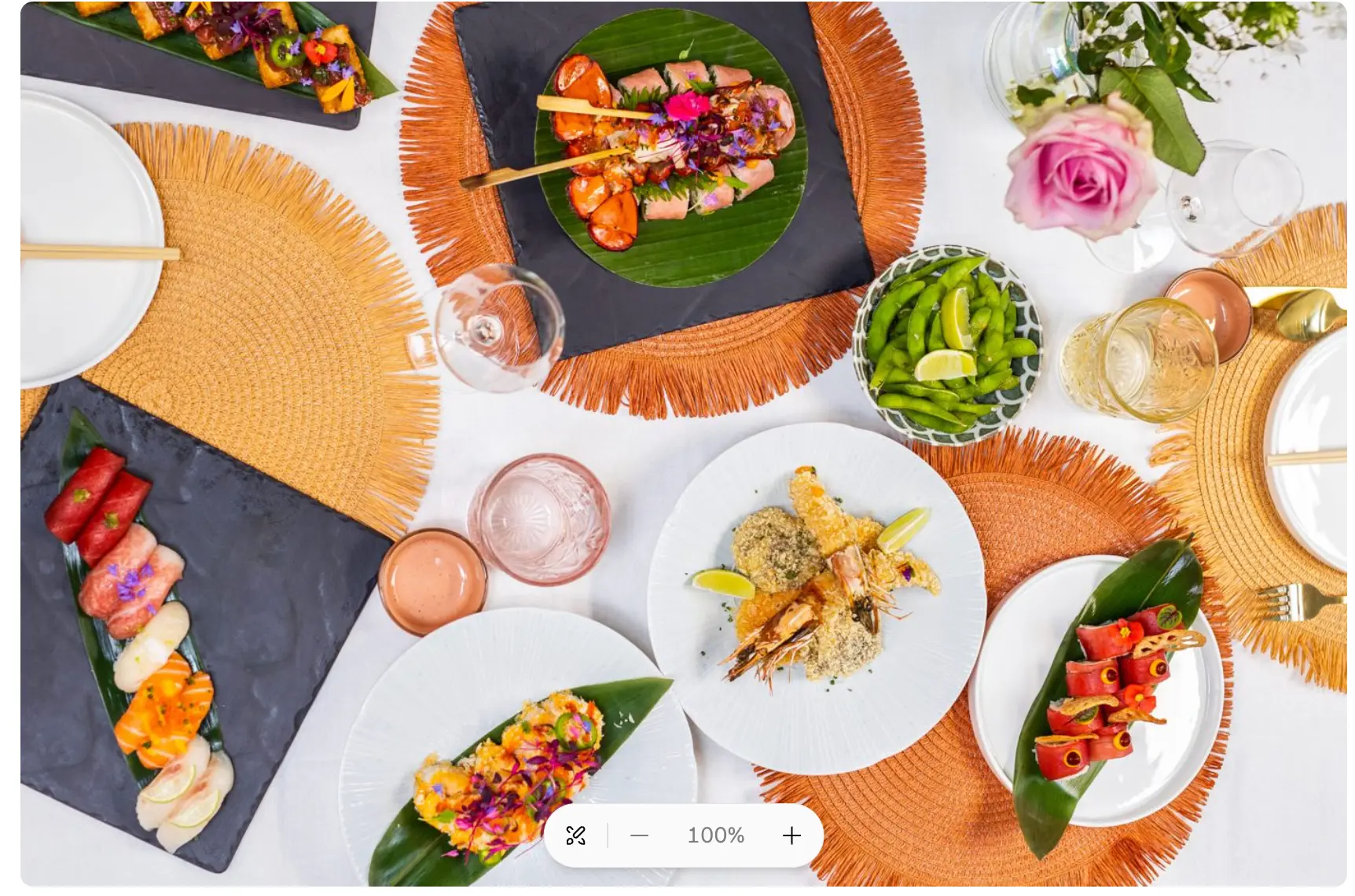 Overvloedig gedekte tafel van bovenaf met sushi, sashimi, tempura en bloemen